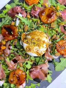 Close up of apricot salad with burrata pistachios and balsamic drizzle presentation