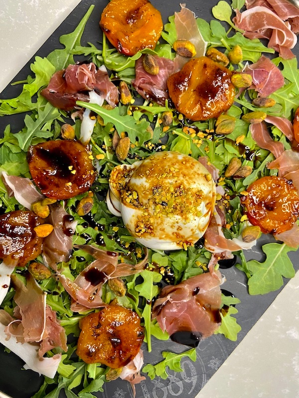 Burrata in the center of the salad with balsamic glaze
