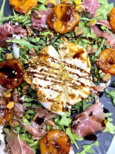 Close up of apricot salad with burrata pistachios and balsamic drizzle