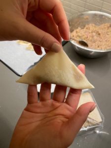 Fold the wonton wrapper in half diagonallly by bringing one corner to the opposite corner. Ensure that all sides are well folded by pressing the sides to avoid the filing from coming out when you cook them. 
