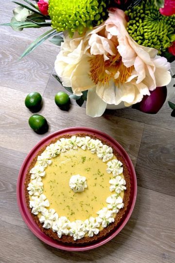 Lime tart presentation next to floral arrangement