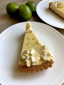 Piece of lime tart with adjacent limes