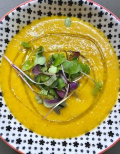 Red lentil soup with drizzle of olive oil and microgreens