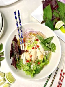 Pho gà bowl with toppings and chopsticks presentation