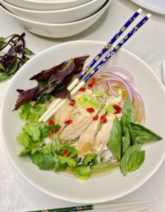 Pho gà noodle bowl with broth and toppings with chopsticks