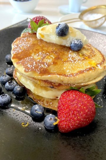 Pancakes served with whipped cream berries and confectioner's sugar