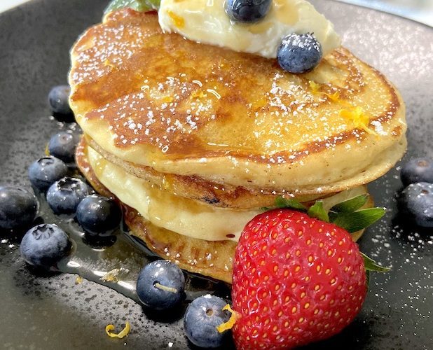 Pancakes served with whipped cream berries and confectioner's sugar
