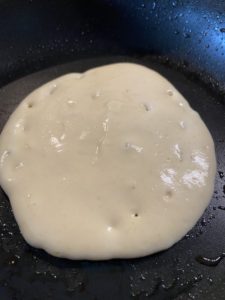 Cooking bubbling pancakes on pan