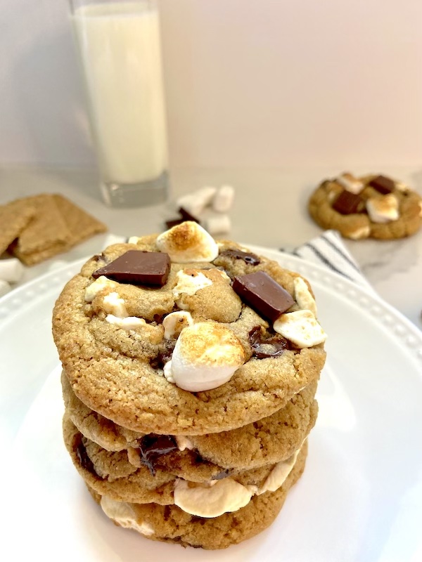 4 chocolate chip s'mores cookies stack with a glass of milk