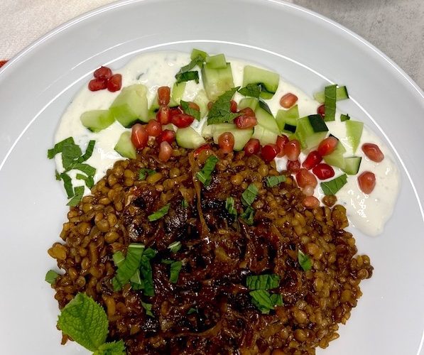Syrian Mujadara dish plated with yoghurt sauce pomegranate Leeds and cucumbers - cropped picture