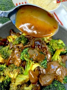 Close up picture of the beef and broccoli stir-fry with sauce dripping from spoon.
