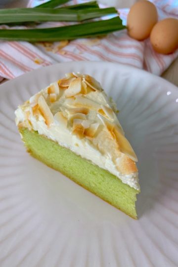 piece of pandan chiffon cake with whipped cream frosting on plate.