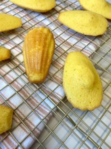 Madeleines resting on a wire rack.