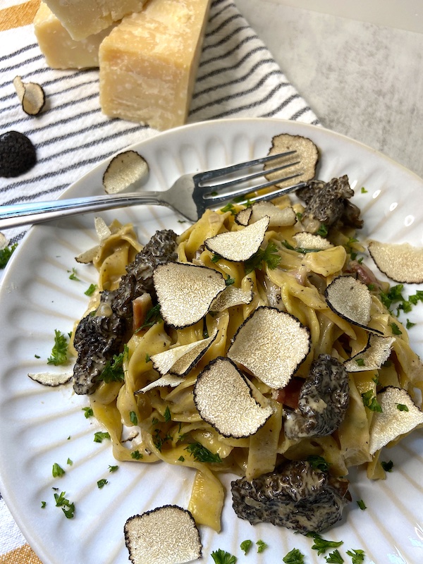 Plate of creamy truffle and morel pasta served with chopped parsley.
