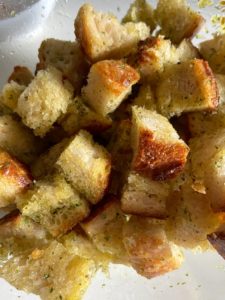 Coating croutons with olive oil mixture.