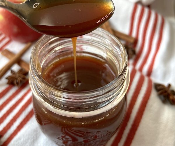 Jar with reduced apple cider on a spoon dripping down