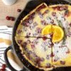 An iron skillet with the Cranberry ornage Ducth baby with a quarter slice